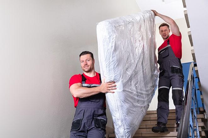 heavy lifting workers transporting a box spring out of a building in Escondido, CA